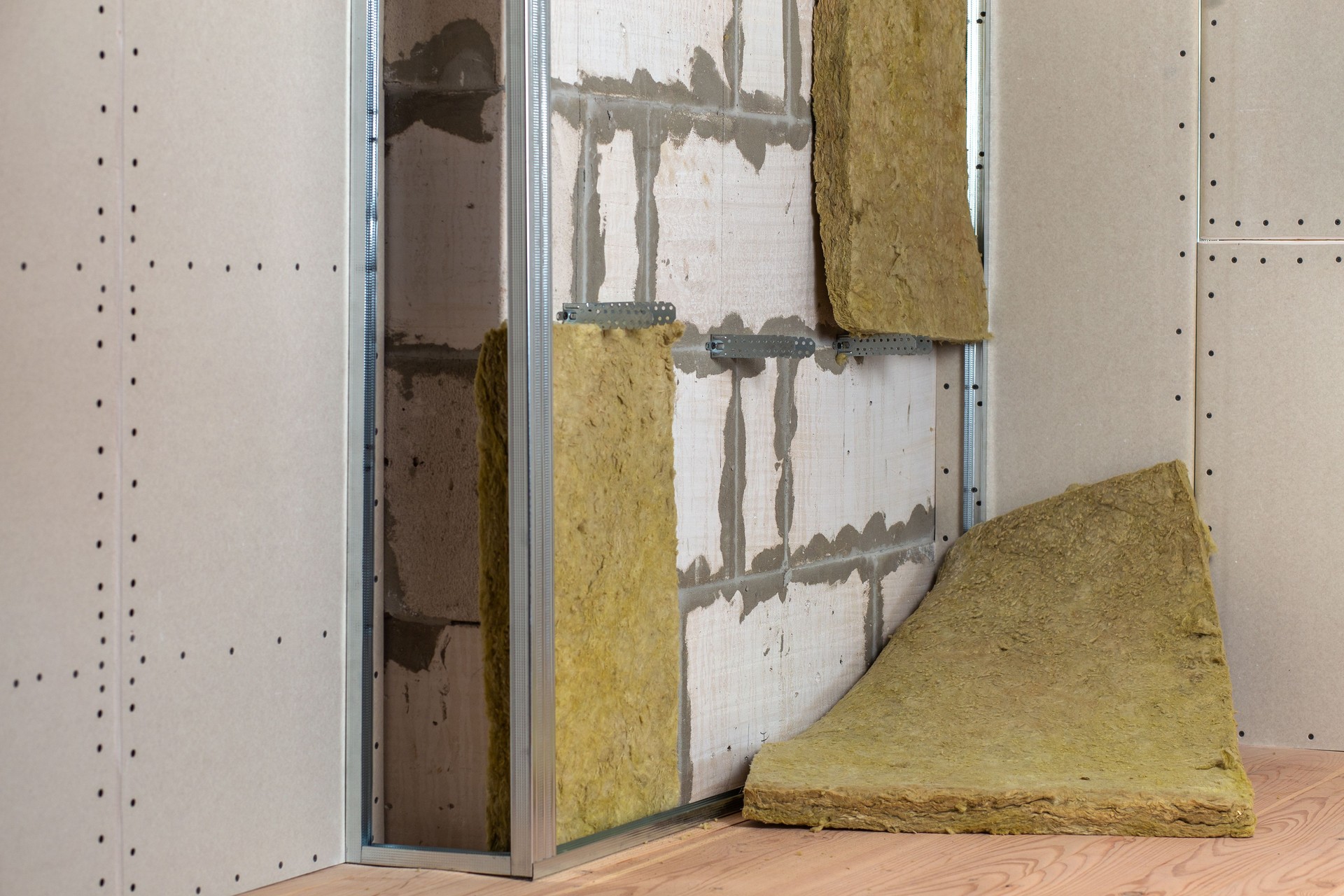 Mur d’une pièce en cours de rénovation avec isolation en laine de roche minérale et cadre métallique préparé pour les plaques de cloison sèche.